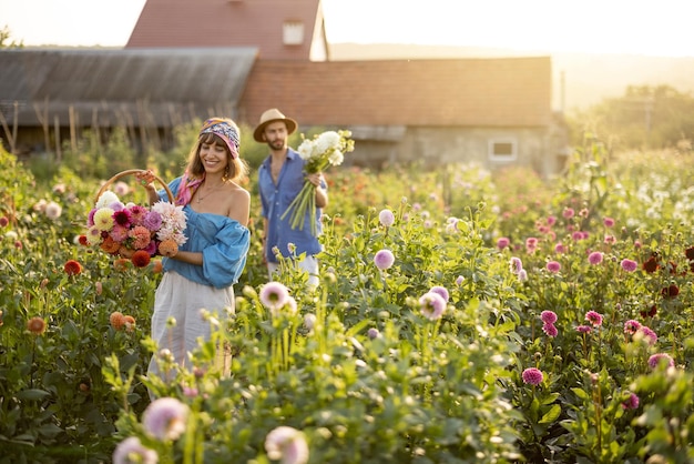 Homem e mulher pegam flores na fazenda ao ar livre