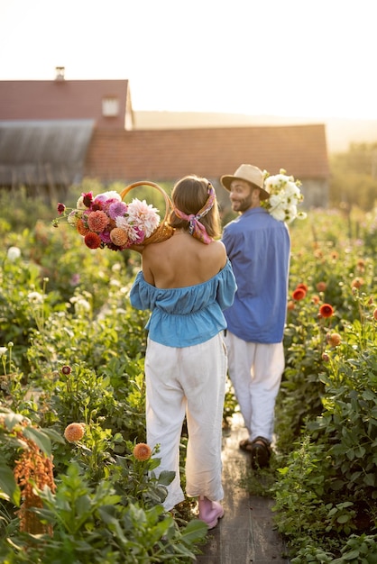 Homem e mulher pegam flores na fazenda ao ar livre