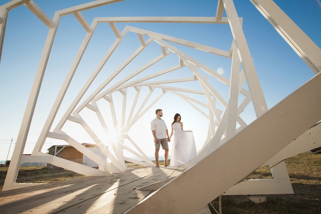 Homem e mulher posando. Estruturas geométricas de madeira. A noiva e o noivo.