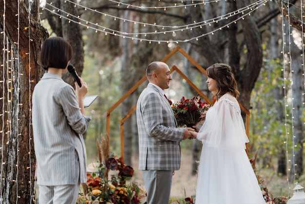 Homem e mulher se envolveram na floresta de outono em uma cerimônia decorada de casamento