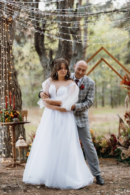 Homem e mulher se envolveram na floresta de outono em uma cerimônia decorada de casamento