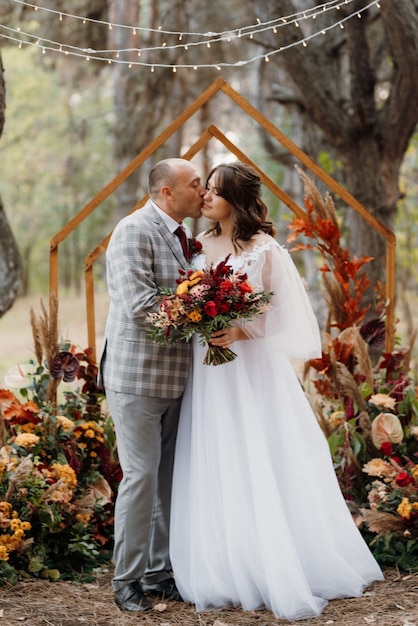 Homem e mulher se envolveram na floresta de outono em uma cerimônia decorada de casamento