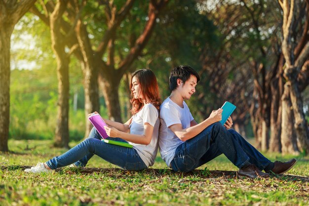 homem e mulher sentada e lendo um livro no parque