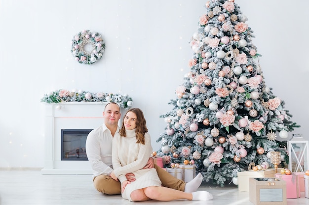 Homem e mulher sentados perto da árvore de Natal