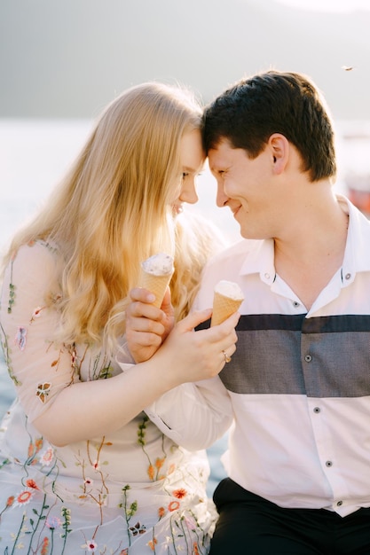 Homem e mulher sorrindo sentados ao lado de um sorvete nas mãos