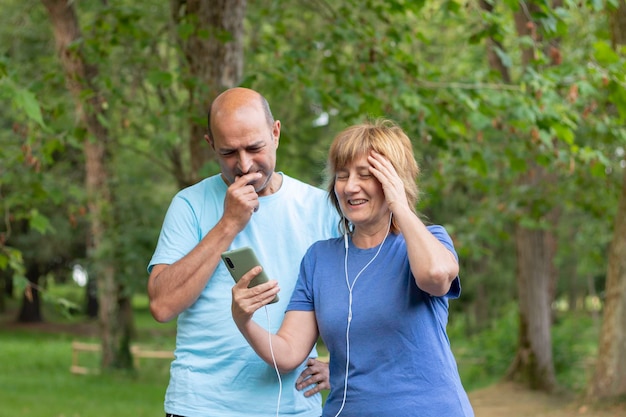 Homem e mulher surpresos com um meme no celular enquanto ouvem música com fones de ouvido