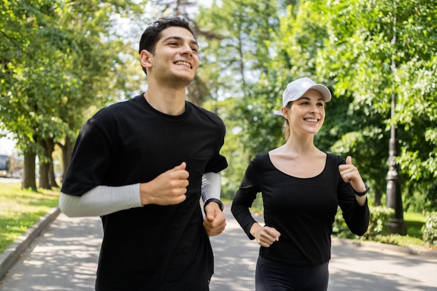 Homem e mulher treinando correndo no parque Um jovem casal feliz fazendo esportes um relógio de fitness