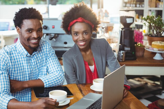 Homem e mulher usando um laptop enquanto tomar café