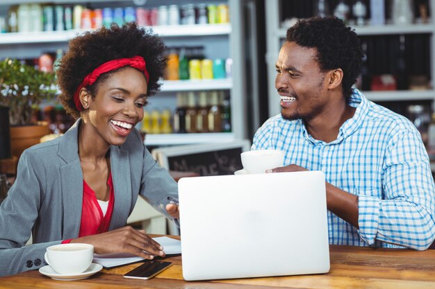 Homem e mulher usando um laptop enquanto tomar café