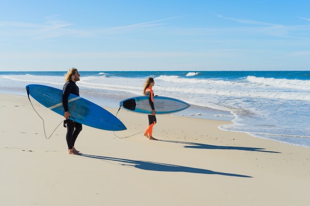 homem e mulher vão ao oceano com pranchas de surf. homem e menina vão surfando