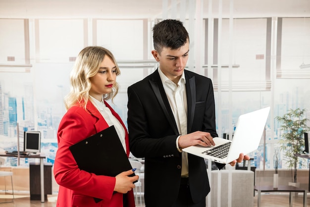 homem e mulher vestem terno discutindo negócios e tendo uma sessão de brainstorming olhando para o laptop em um escritório moderno