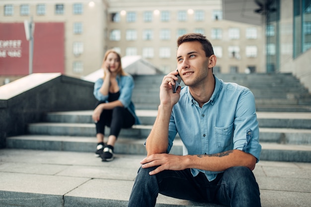 Homem e mulher viciados em telefone falando por smartphones, viciados em redes sociais, estilo de vida moderno