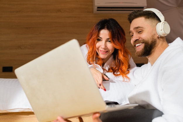 Foto homem e uma mulher vestida de roupões de banho com laptop