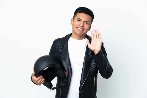 Homem ecudoriano com capacete de motociclista isolado no fundo branco saudando com a mão com expressão feliz