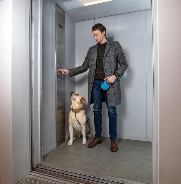 Homem elegante bonito em pé com cachorro labrador no elevador