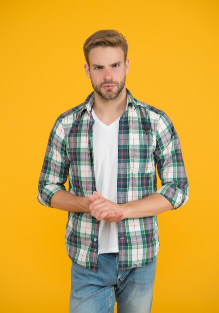 Homem elegante com roupas da moda. homem bonito em jeans e camisa quadriculada. fundo amarelo do estudante carismático. Faça você parecer bem. moda casual para homens. Roupas masculinas e aparência.