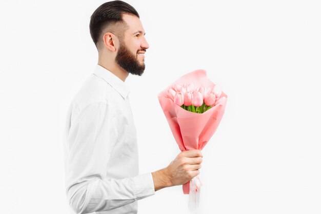 Homem elegante com uma barba segurando um buquê de tulipas, um presente para o dia dos namorados