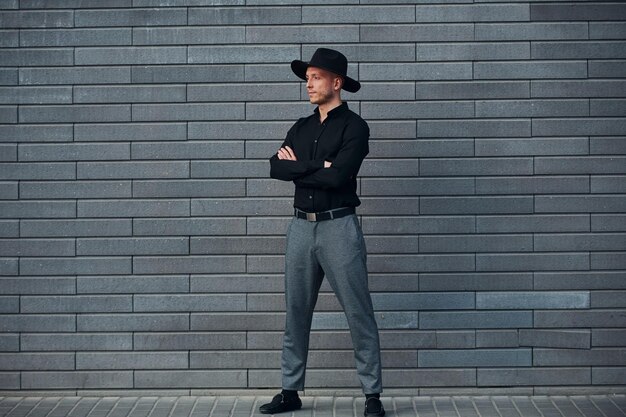 Homem elegante elegante em pé ao ar livre contra parede cinza