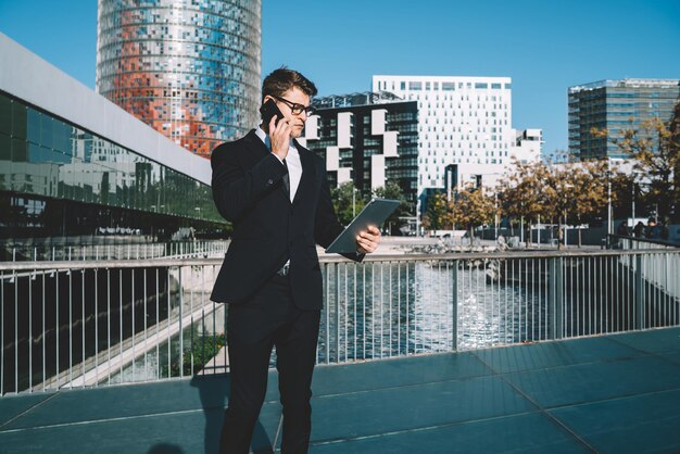 Homem elegante falando no telefone contra a paisagem urbana