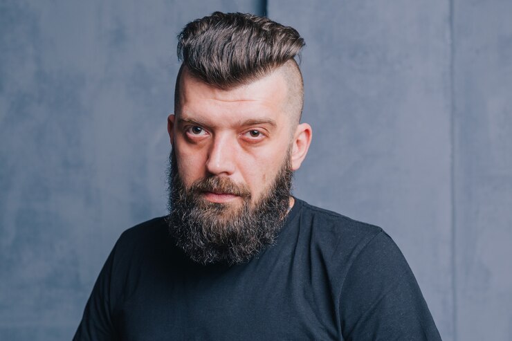 Foto homem elegante hippie barbudo. retrato de um homem moreno com uma barba. corte de cabelo elegante para um homem.
