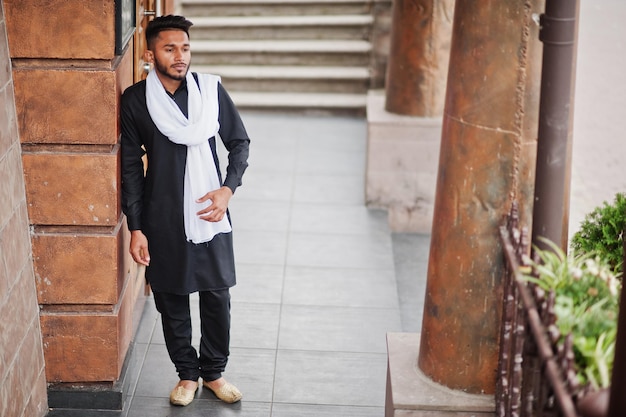 Homem elegante indiano em roupas tradicionais pretas com lenço branco posado ao ar livre