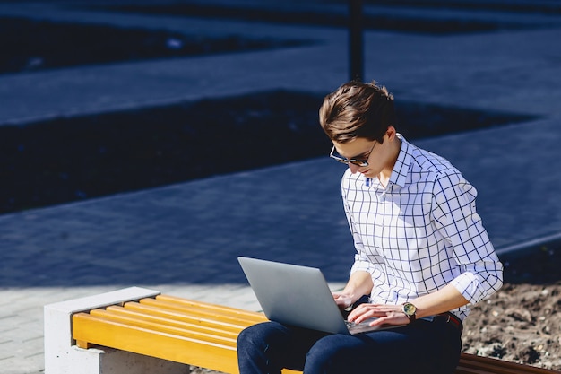 Homem elegante, trabalhando no laptop na rua