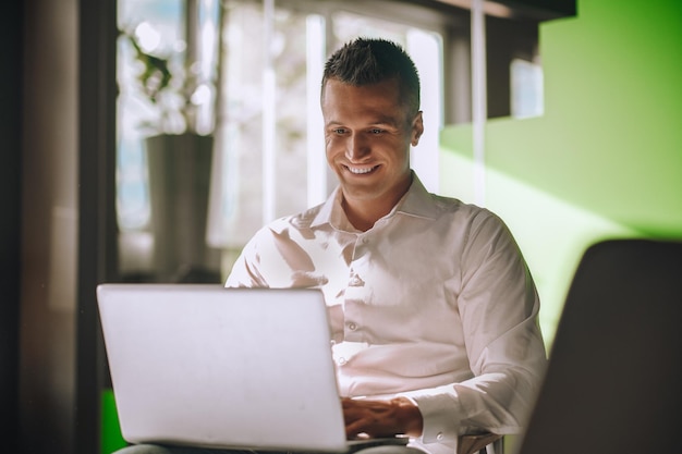 Homem elegante trabalhando no laptop sentado na cadeira