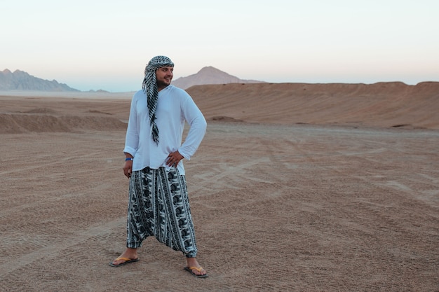 Homem em arafat e roupas beduínas no deserto em safári