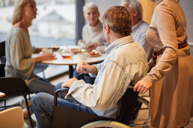 Homem em cadeira de rodas juntando amigos no café