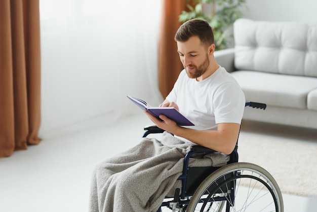 Homem em cadeira de rodas lendo um livro em casa