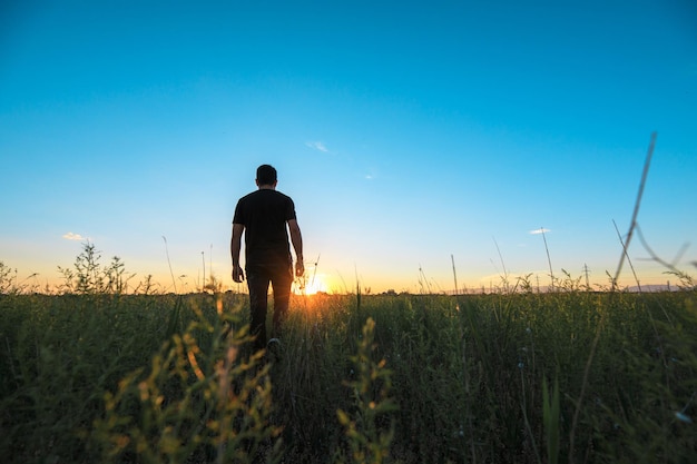 Homem em campo ao pôr do sol