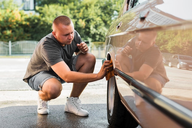 Foto homem em cena completa limpando a roda do carro