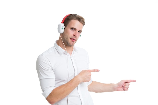 Homem em fones de ouvido, apontando o dedo indicador isolado no branco. A central de atendimento do assistente ajuda a encontrar a direção. O trabalhador de serviço de chamada de cara mostra a direção. Veja este guia. Homem ouve fones de ouvido de música.