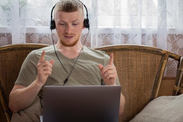 Foto homem em fones de ouvido gesticulando se comunica em redes sociais na casa de campo