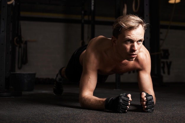 Homem em forma de prancha no ginásio