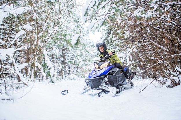 Homem em moto de neve na montanha de inverno