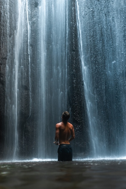 Homem em pé sob a impressionante cachoeira em Bali, Indonésia