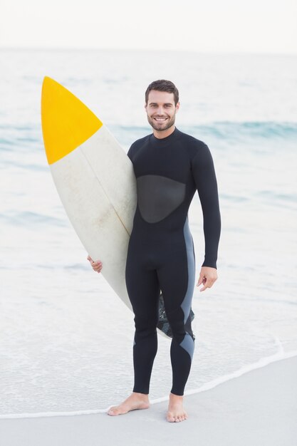 Homem em roupa de mergulho com prancha de surf em um dia ensolarado