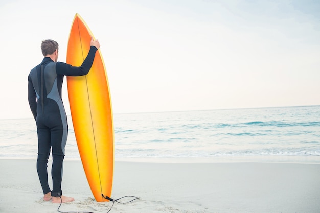 Homem em roupa de mergulho com prancha de surf em um dia ensolarado