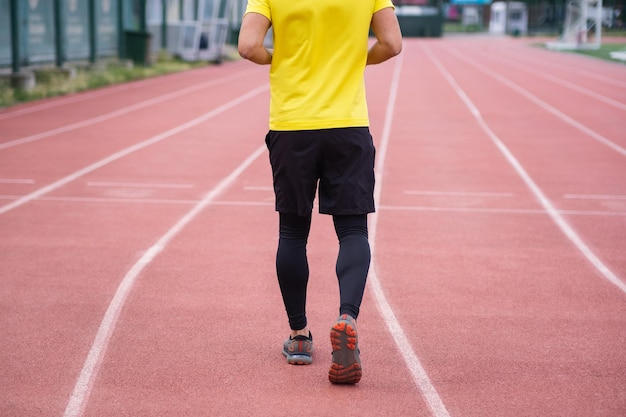 Homem em roupas esportivas correndo e correndo energicamente na pista do estádio, ativo e saudável