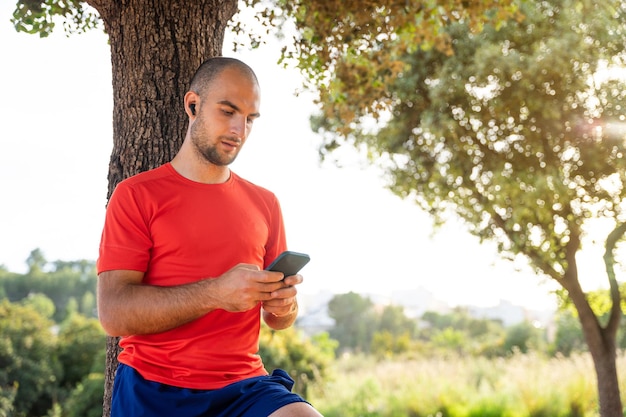 Homem em roupas esportivas usando telefone celular e fones de ouvido