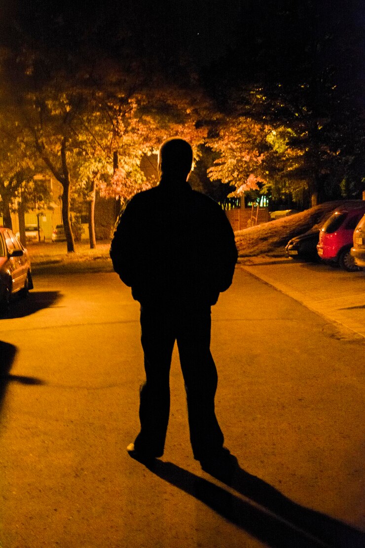 Foto homem em silhueta de pé na rua à noite