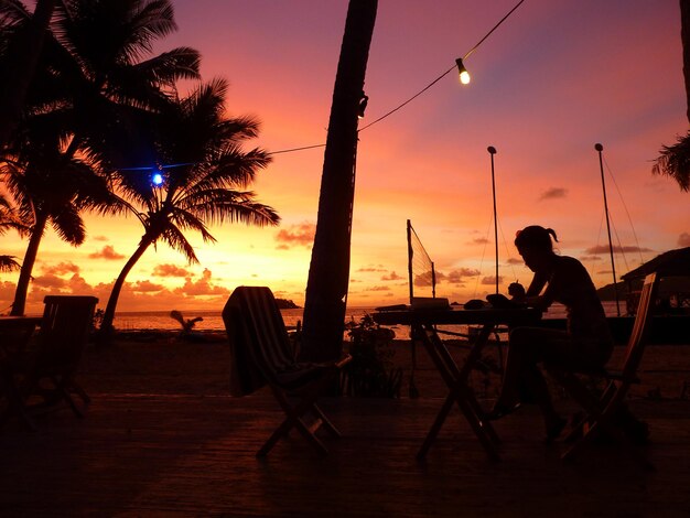 Foto homem em silhueta na praia contra o céu durante o pôr do sol