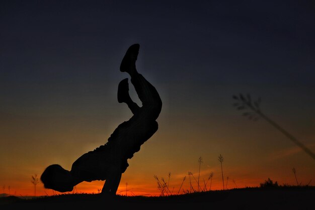 Foto homem em silhueta se exercitando no campo contra o céu durante o pôr do sol