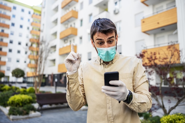 Homem em traje de proteção com máscara digitando no celular smartphone, caso de infecção de vírus, contaminação de germes ou bactérias. Prevenção de infecções e controle de epidemia.