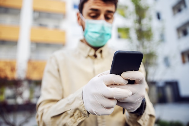 Homem em traje de proteção com máscara digitando no celular smartphone, caso de infecção de vírus, contaminação de germes ou bactérias. Prevenção de infecções e controle de epidemia.