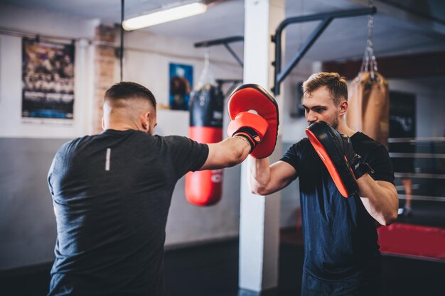 Homem em treinamento de boxe com instrutor em um ginásio