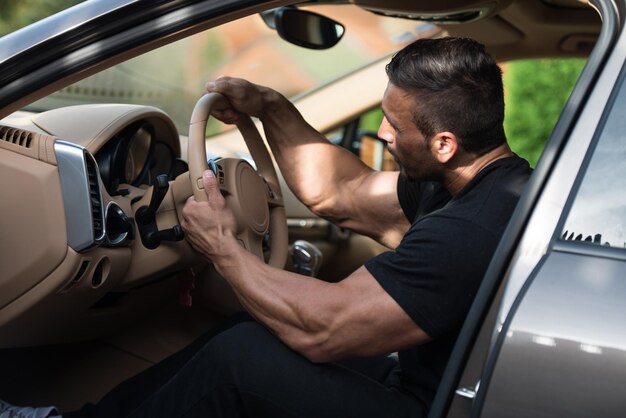 Homem em um agasalho dirigindo no carro