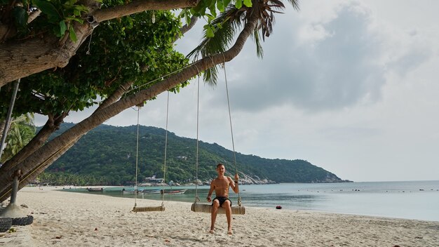 Homem em um balanço na praia. Koh Pangan. Tailândia.