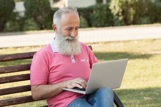 Foto homem em um banco usando um laptop